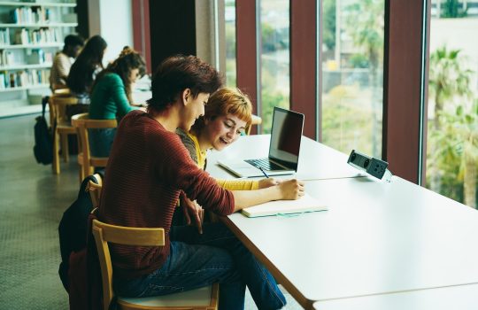 Young multiethnic group of students studying inside university library - Focus on asian guy face